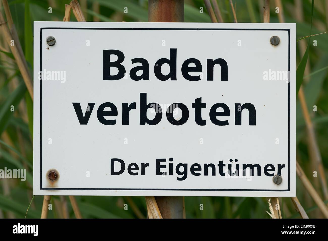 Prohibition sign at a private lake in Germany. Translation: Bathing prohibited, the owner Stock Photo
