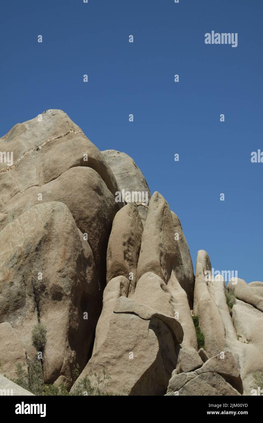 A vertical shot of big rock formation under blue bright sky Stock Photo