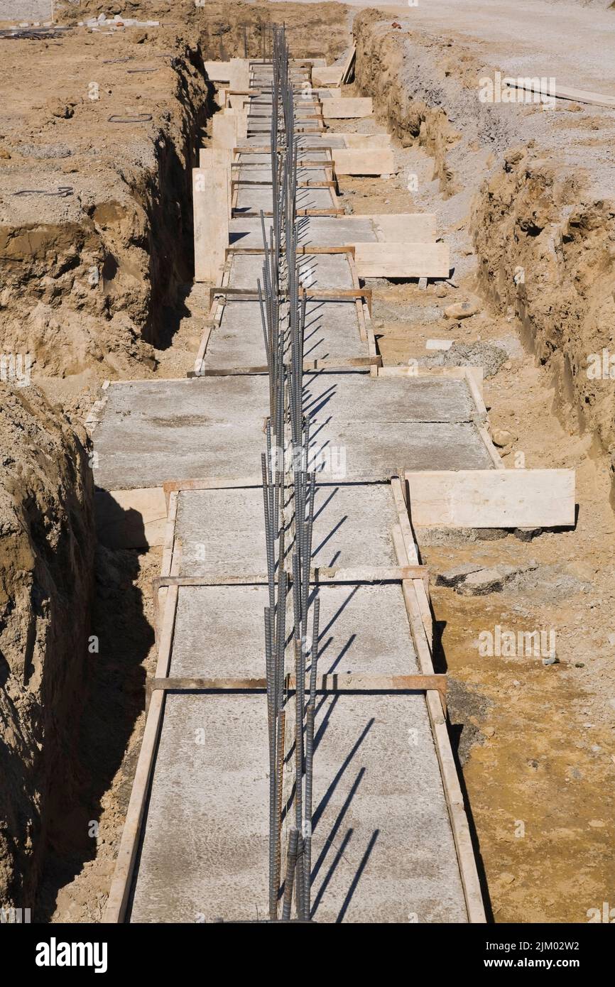 Trench at construction site with reinforced concrete footings for supporting the foundation wall of a building. Stock Photo