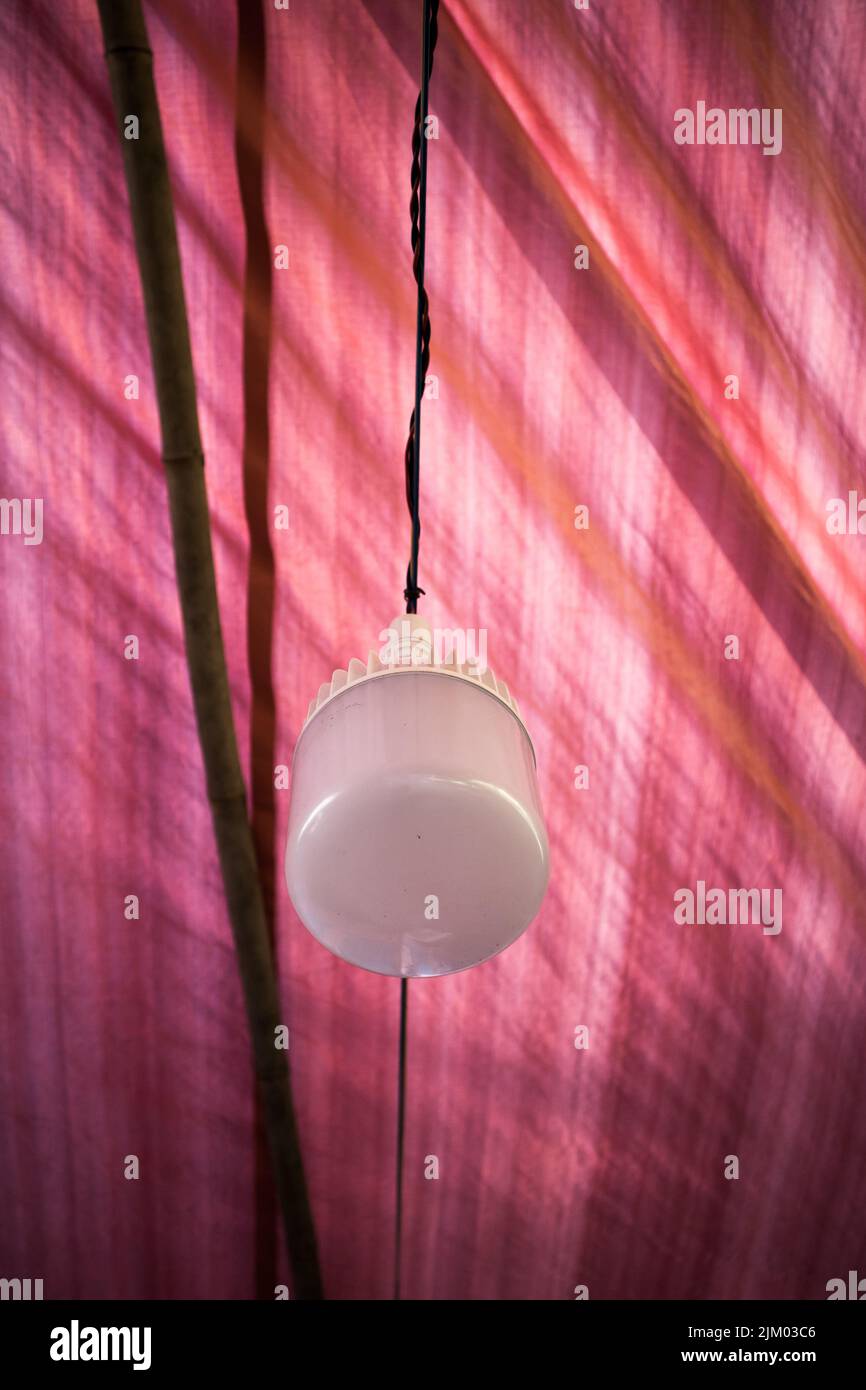 A white LED bulb hanging from the wire which is decorated in a village puja pandal Stock Photo