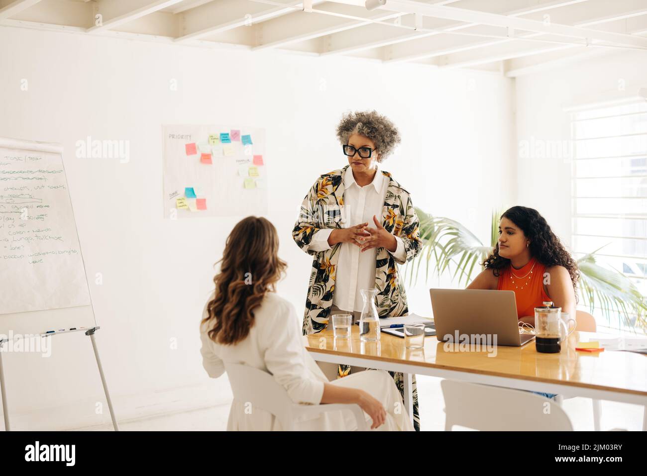 Senior businesswoman having a discussion with her colleagues in a boardroom. Group of businesswomen sharing creative ideas during a meeting. Businessw Stock Photo