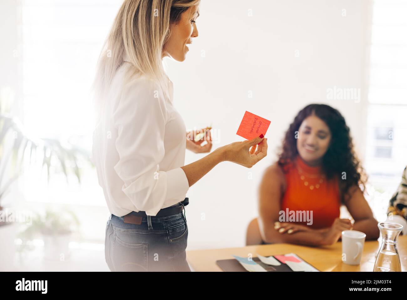 Female entrepreneur presenting her ideas using sticky notes. Young businesswoman brainstorming with her team during a meeting. Creative businesswomen Stock Photo