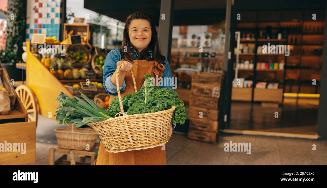 Shop employee with Down syndrome holding a basket of fresh organic
