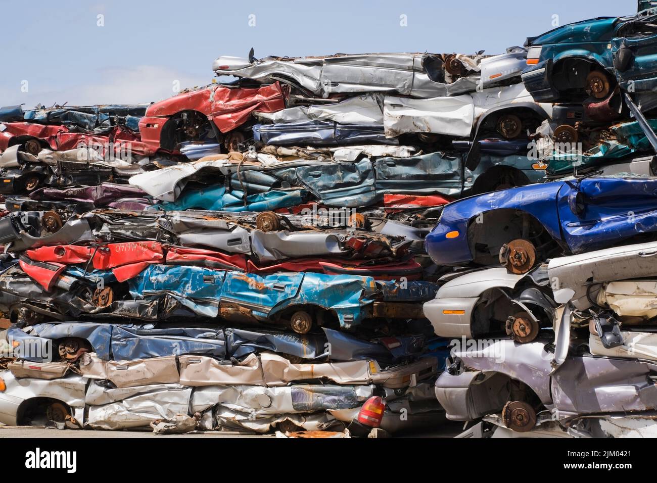 Stacked and crushed discarded automobiles at scrap metal recycling yard. Stock Photo
