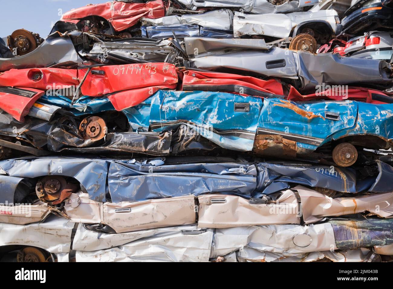 Stacked and crushed discarded automobiles at scrap metal recycling yard. Stock Photo