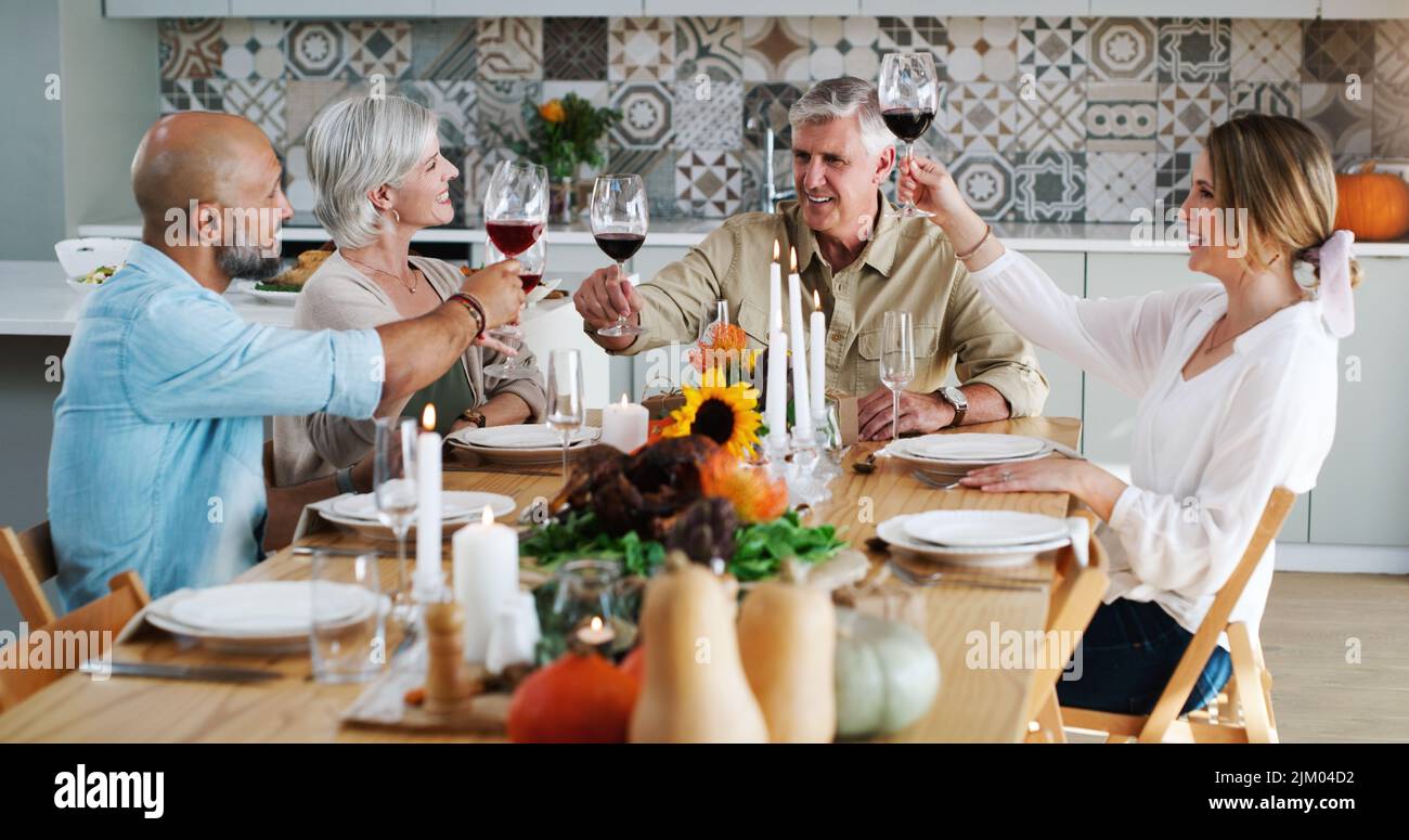 Friends like you are special everyday of the year. two happy couples sitting down for lunch and toasting with wine glasses at home. Stock Photo