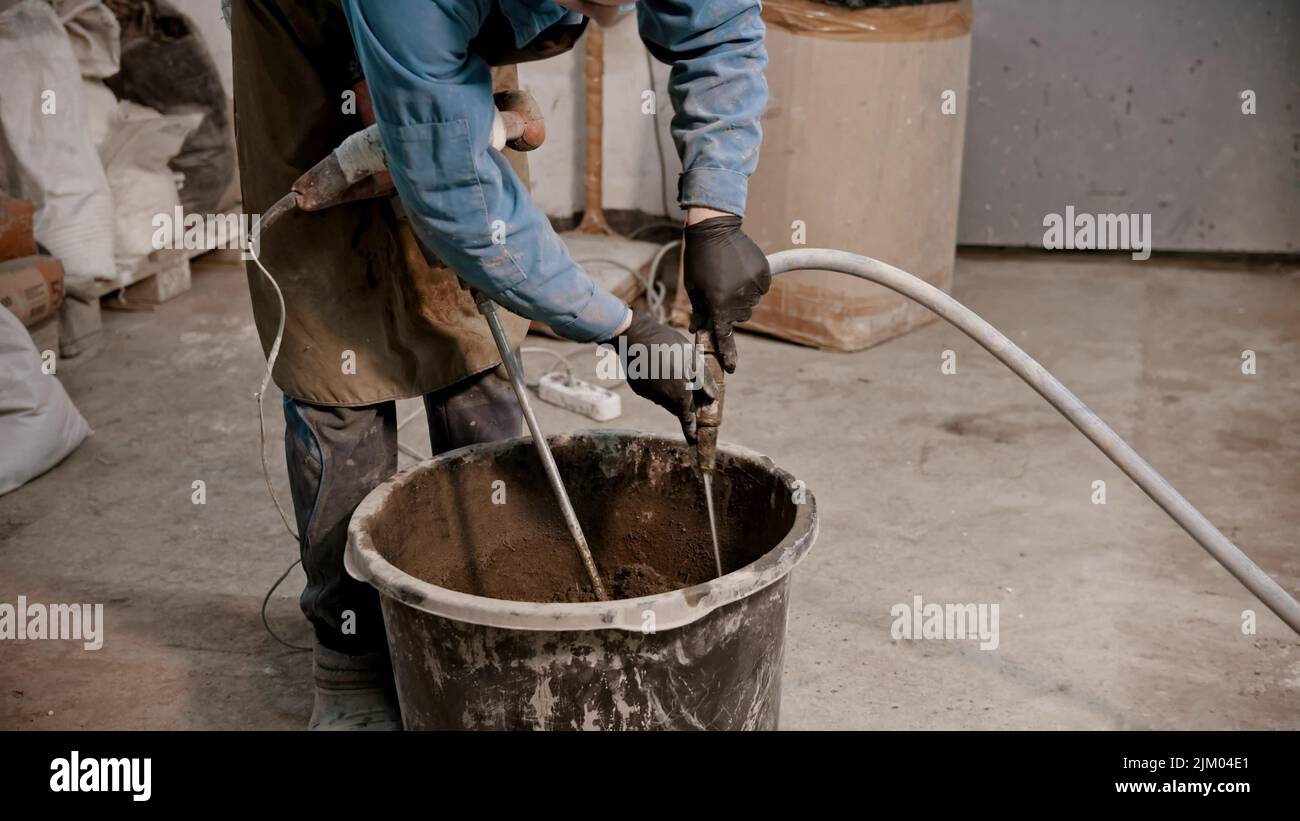 Concrete industry young man worker adding water in the bucket full of