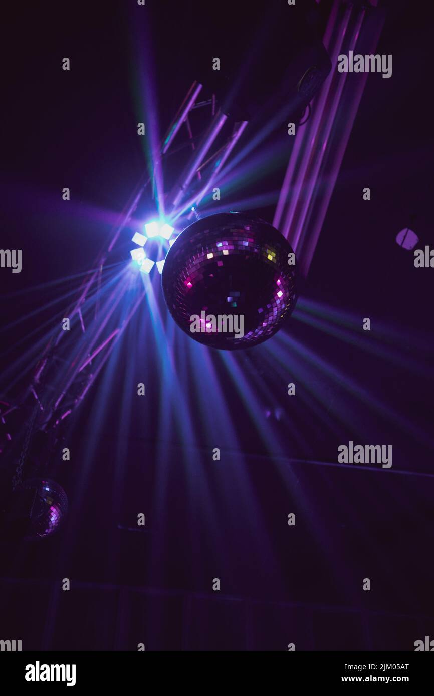 A vertical low angle view of a disco ball against the bright neon lights in the club Stock Photo