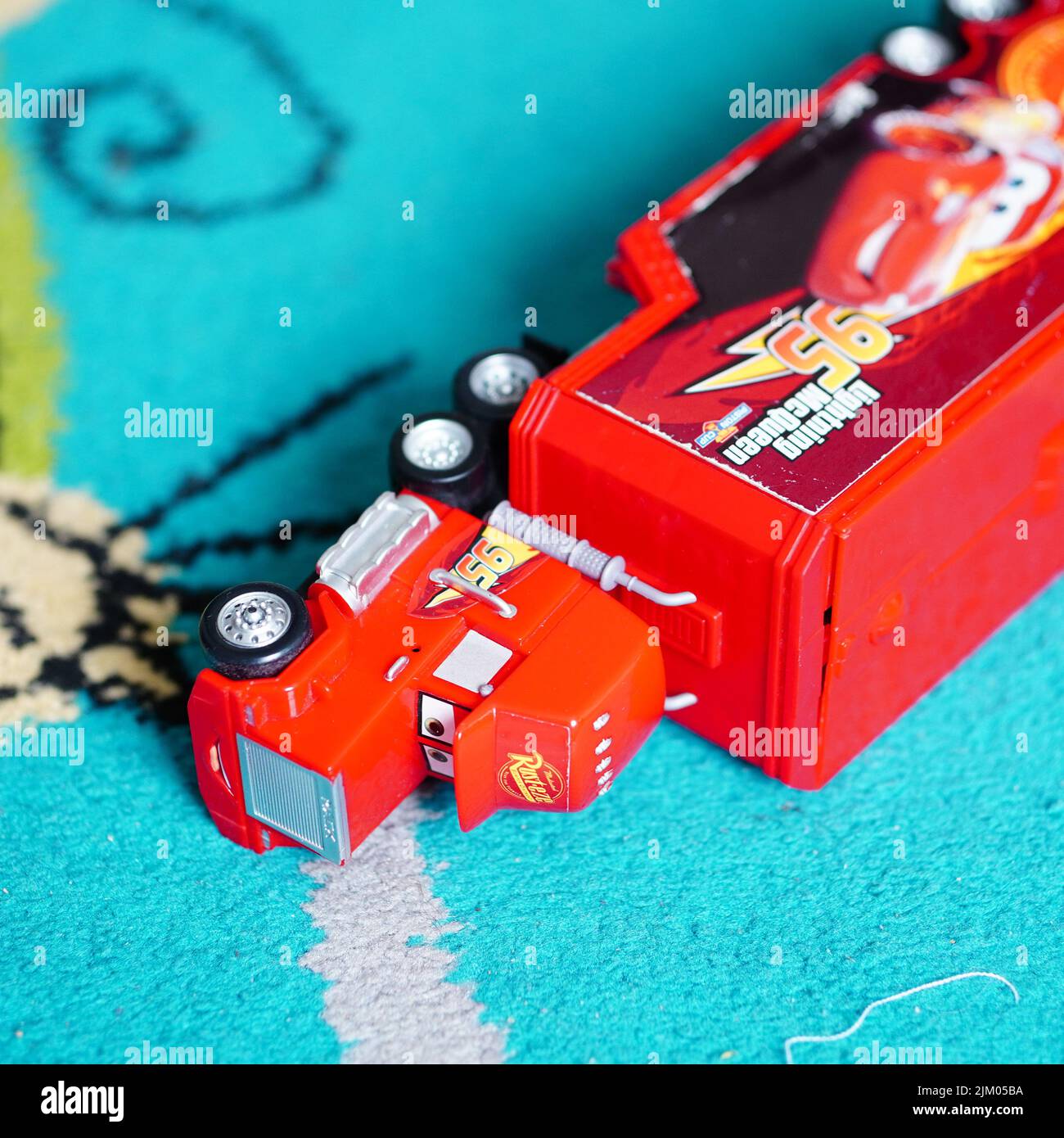 A Mattel brand red toy model truck of the Disney Pixar movie Cars laying on a carpet floor Stock Photo