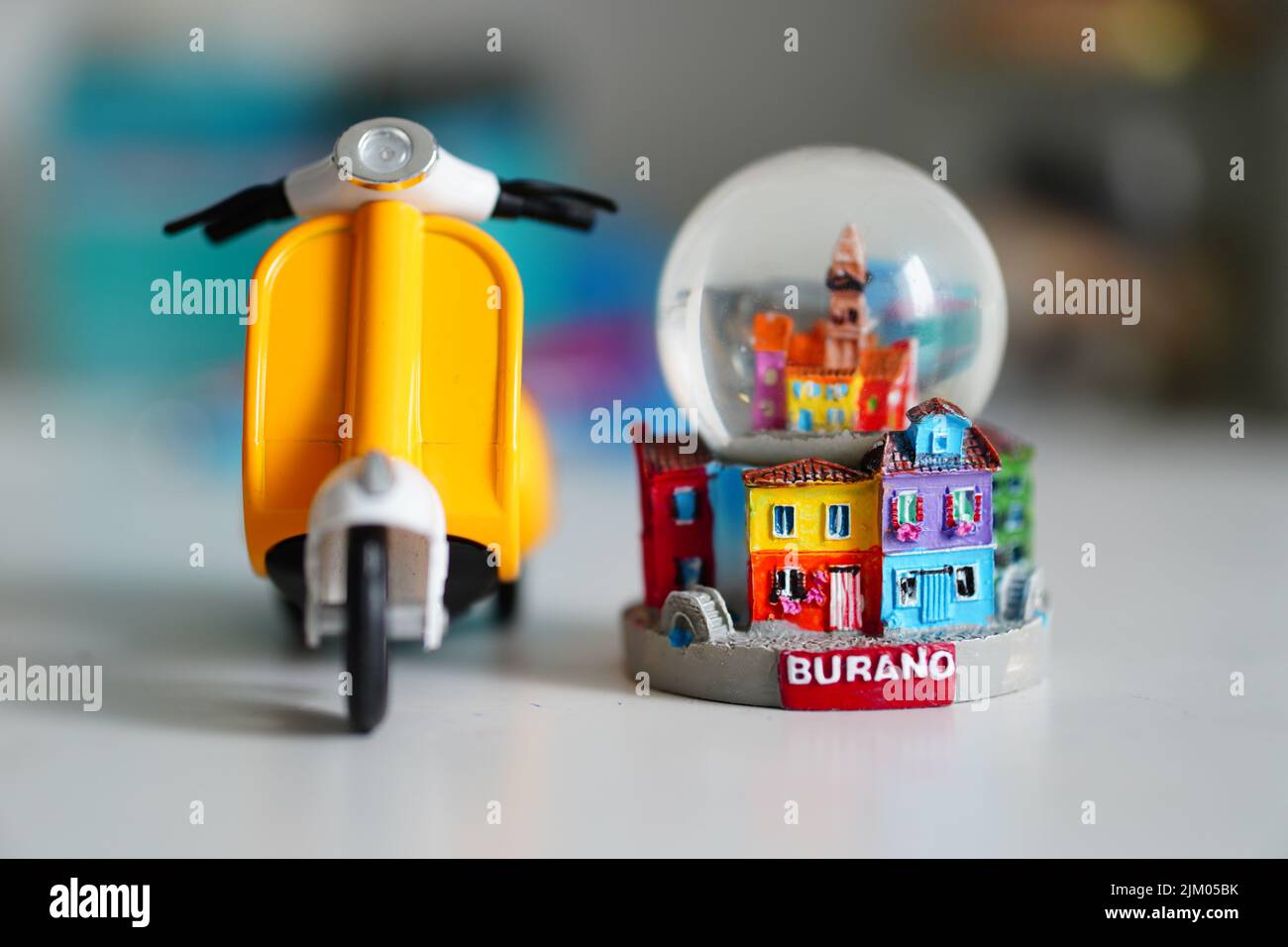 An Italian Burano snowglobe and Vespa scooter toy model on the blurry