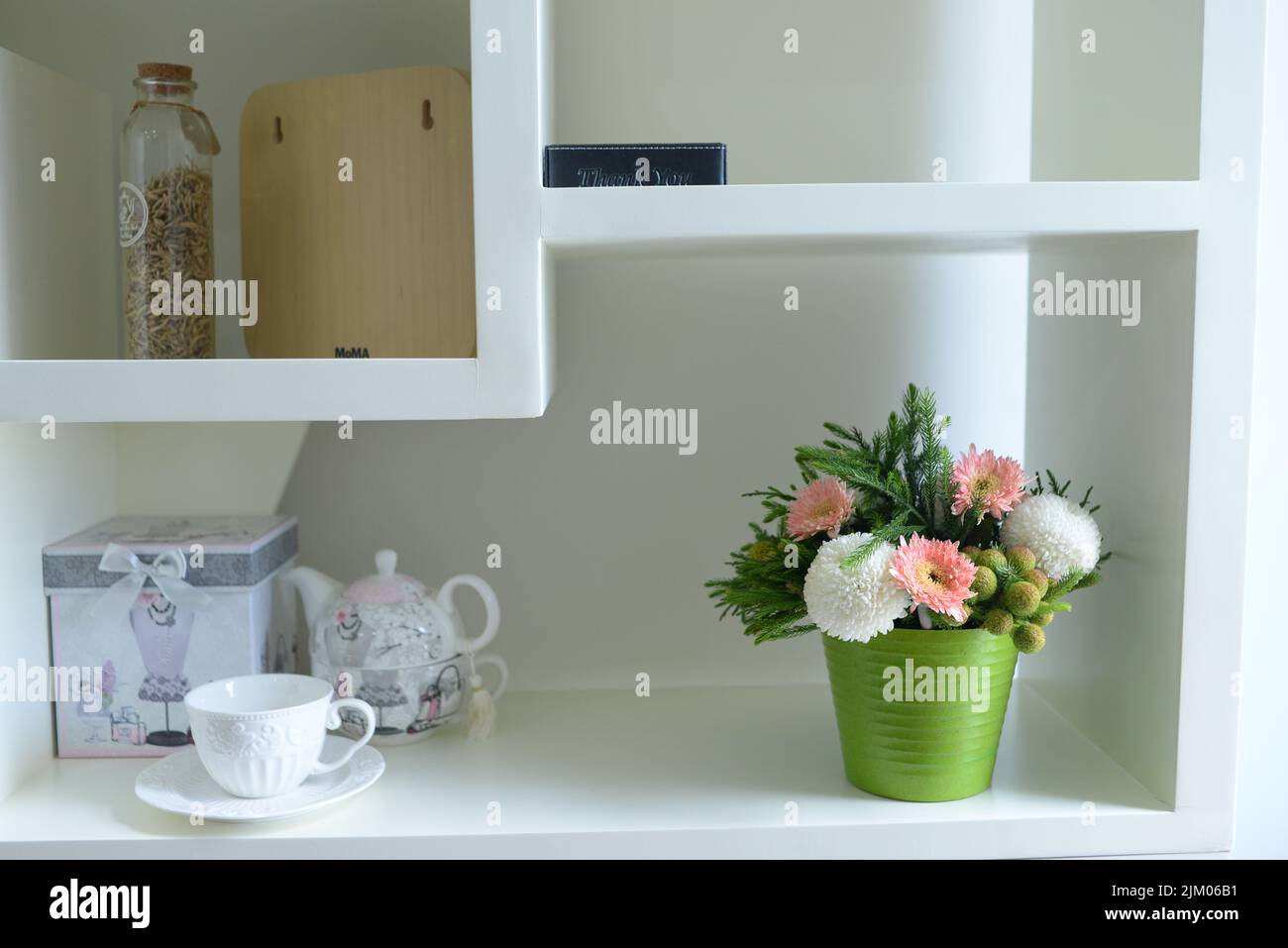 A green vase with a beautiful pink white bouquet on a white shelf Stock Photo