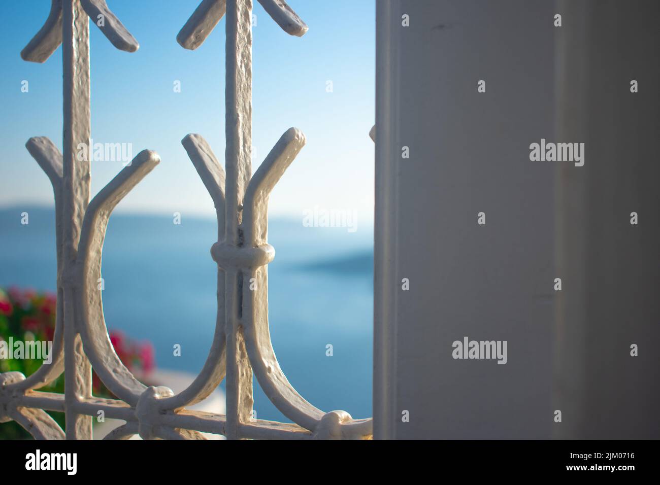 A closeup of a white iron window grill with a view of Santorini in the background Stock Photo