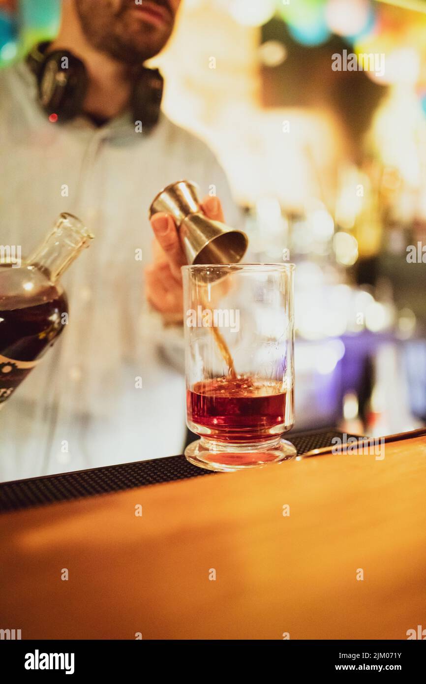 A vertical shot of an alcoholic drink pouring into a glass cup by a barman at a pub Stock Photo