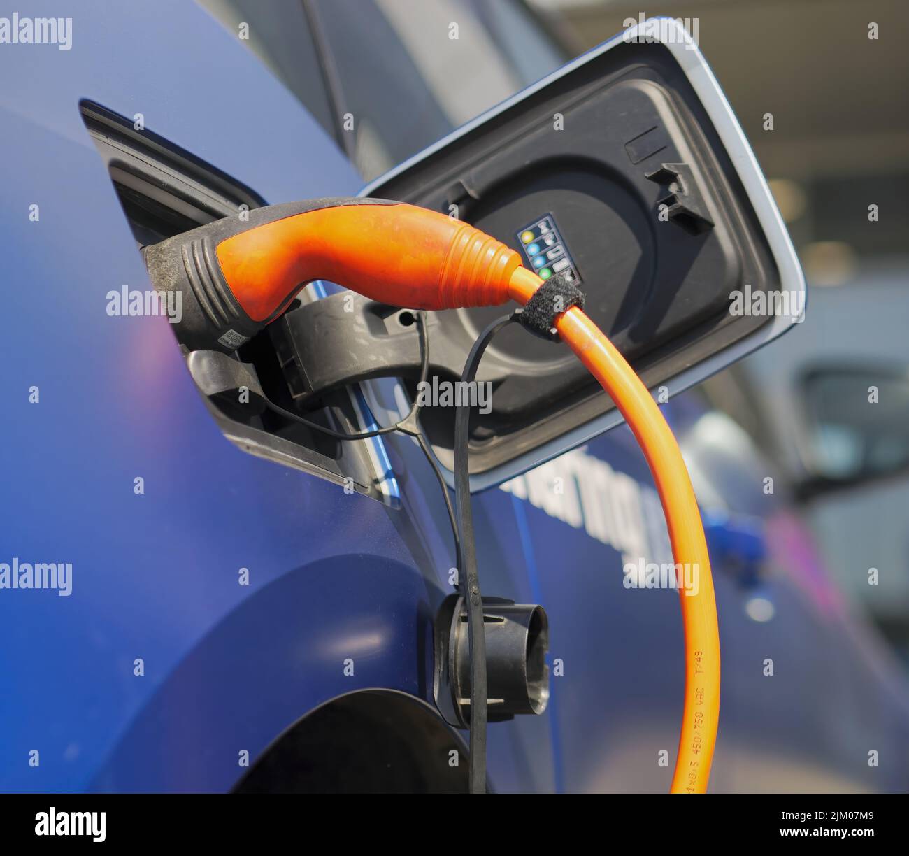 A closeup shot of an electric car being charged with an orange charger Stock Photo