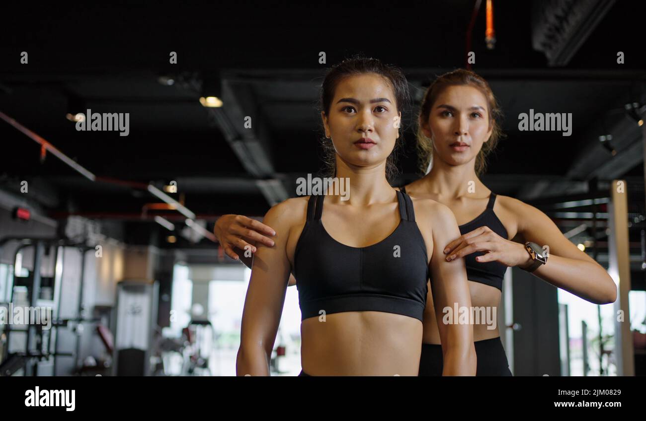 Sporty girl doing weight exercises with the help of her personal trainer at the gym. Stock Photo