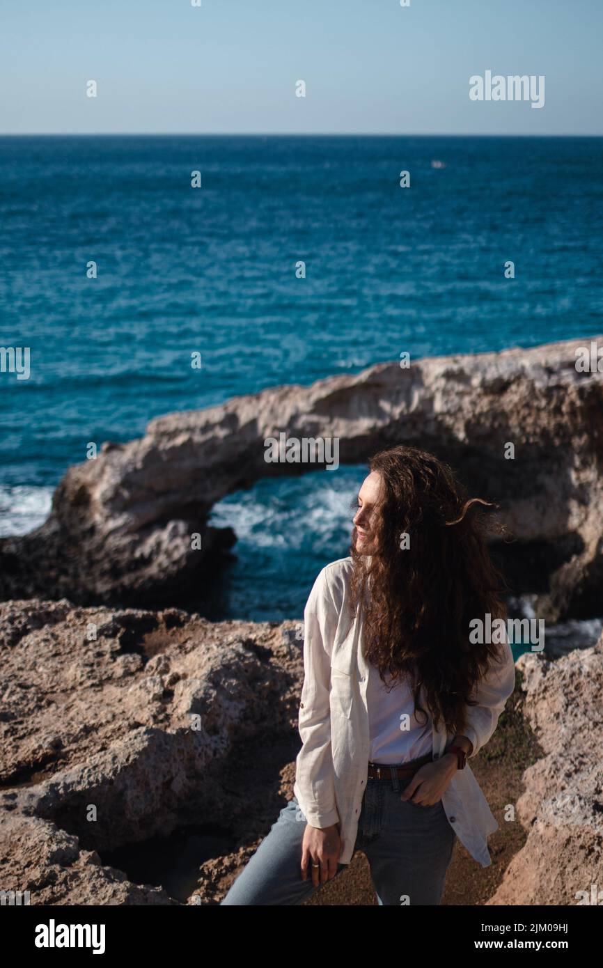 Smiling young woman is standing at the edge near love bridge sea caves Stock Photo