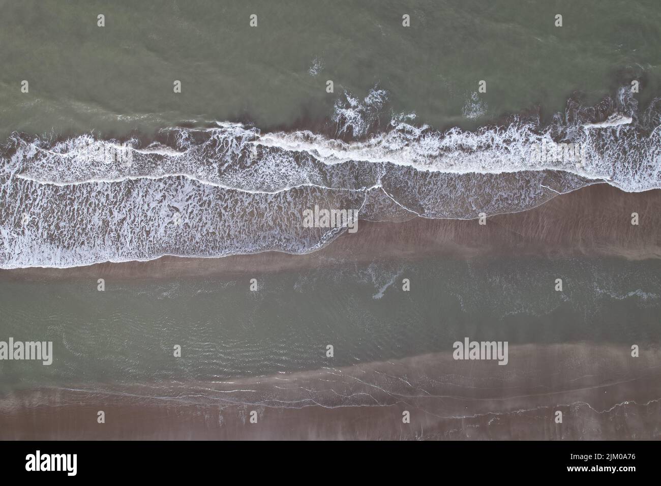 An aerial view of the soft ocean waves with foam on a sandy beach Stock ...