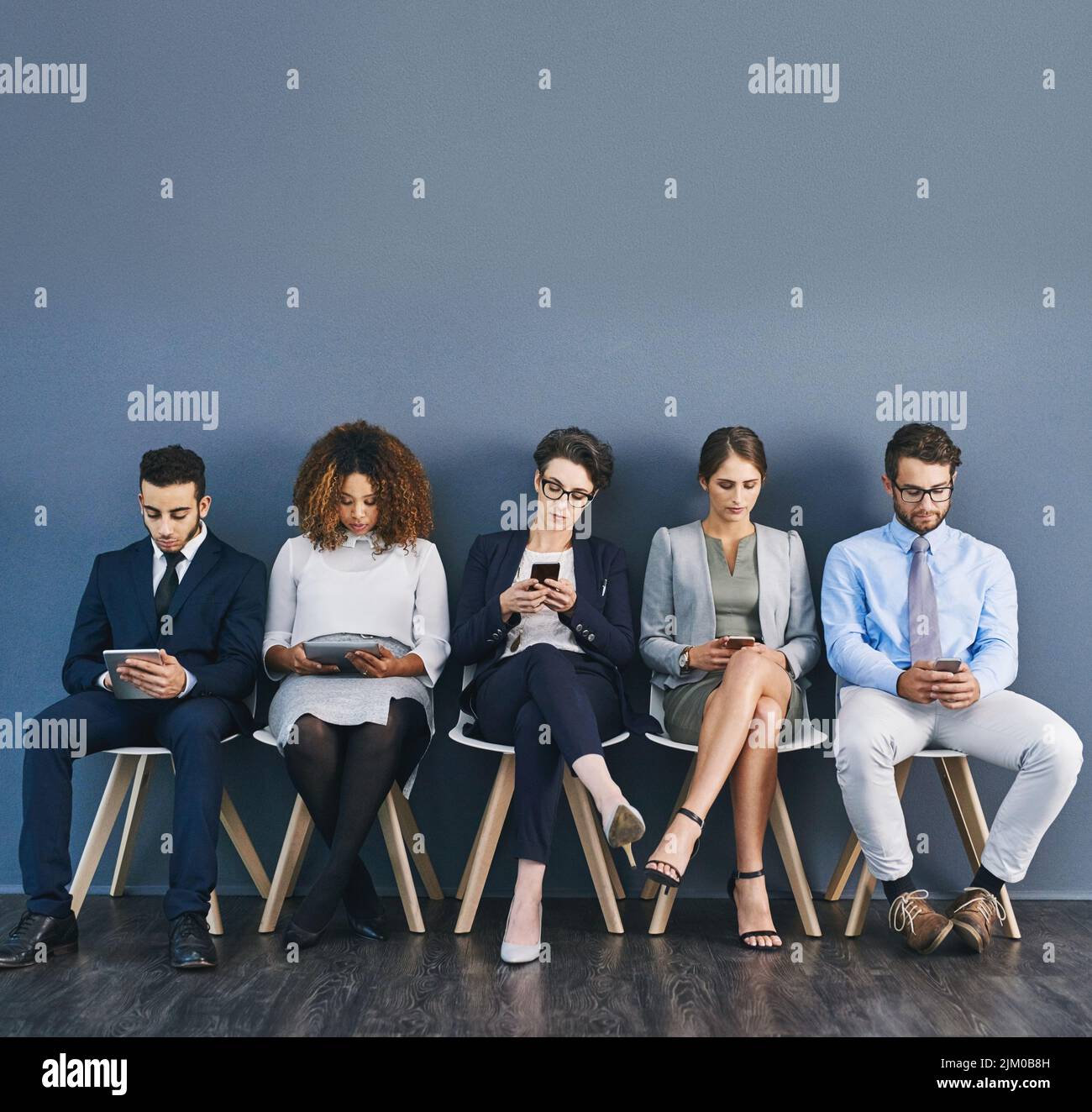 Group of business people at a job interview at a small startup company with copy space. Businesspeople sitting and waiting in line for a meeting with Stock Photo
