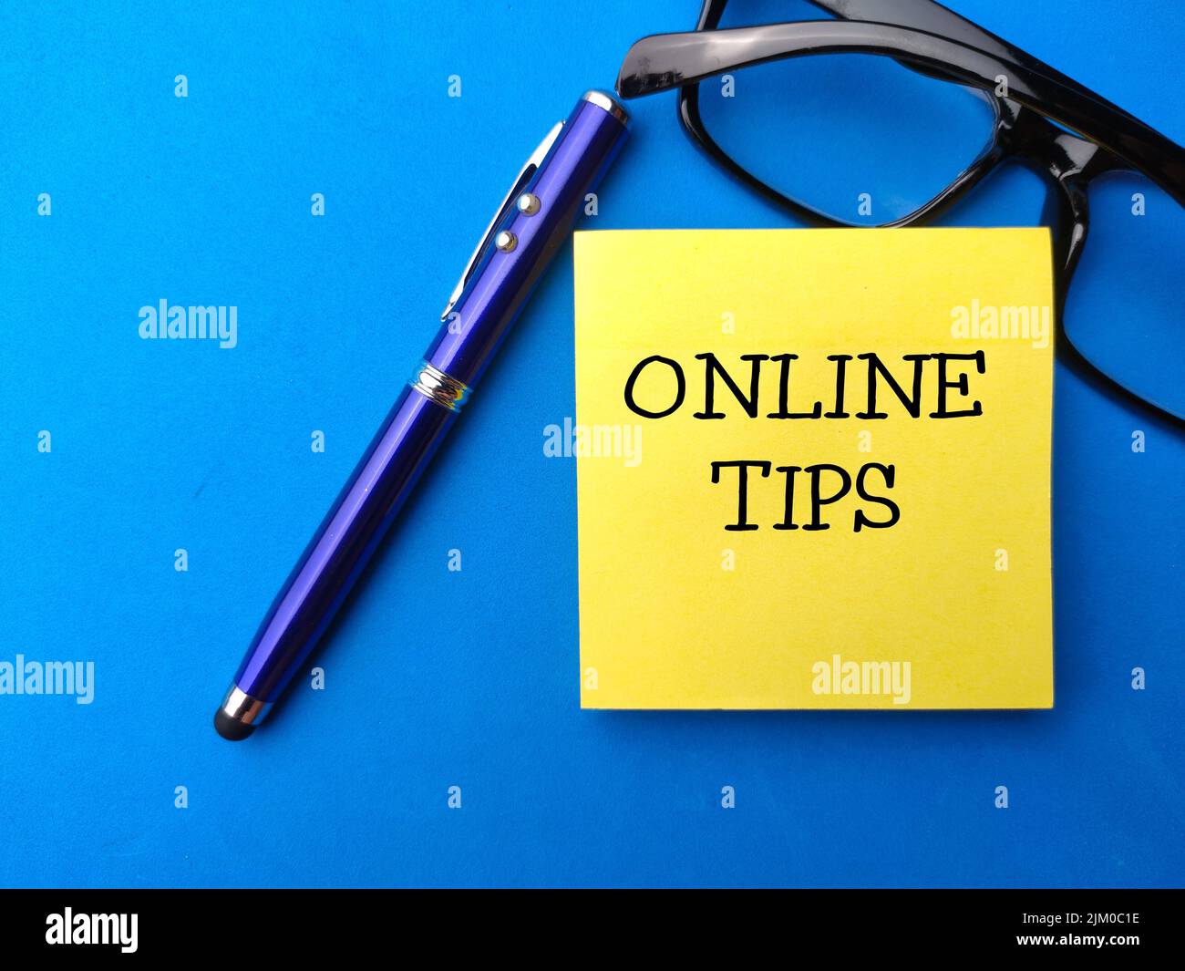 Top view pen,glasess and sticky note with the word ONLINE TIPS. Stock Photo