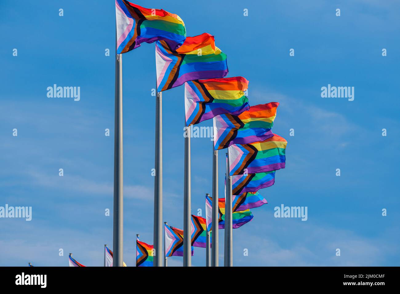 LGBTQ Progress Pride Flags waving over blue sky Stock Photo