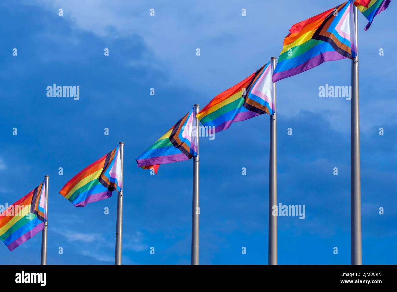 LGBTQ Progress Pride Flags waving over blue sky Stock Photo