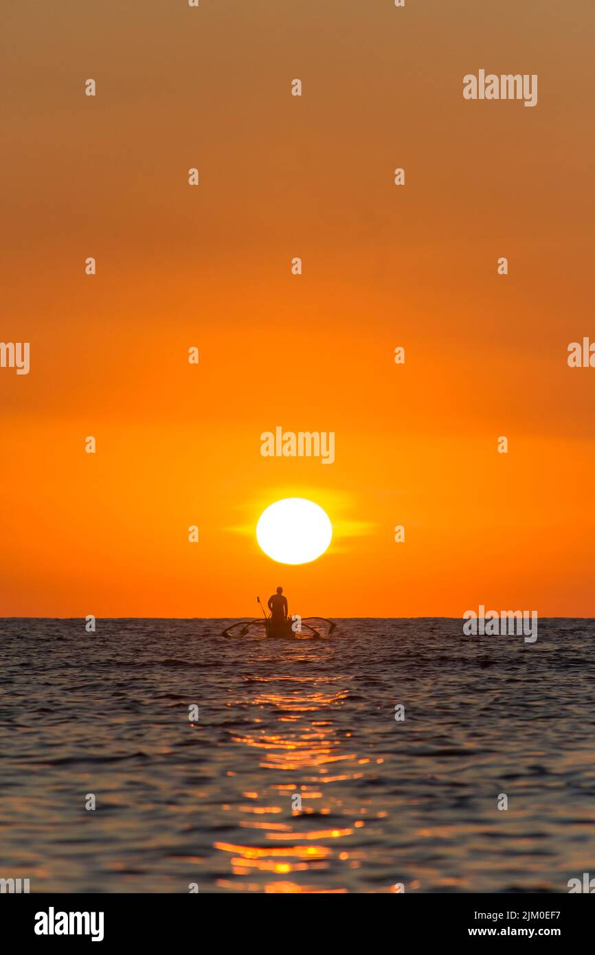 A vertical shot of a silhouette of a person on a boat on the sea at ...