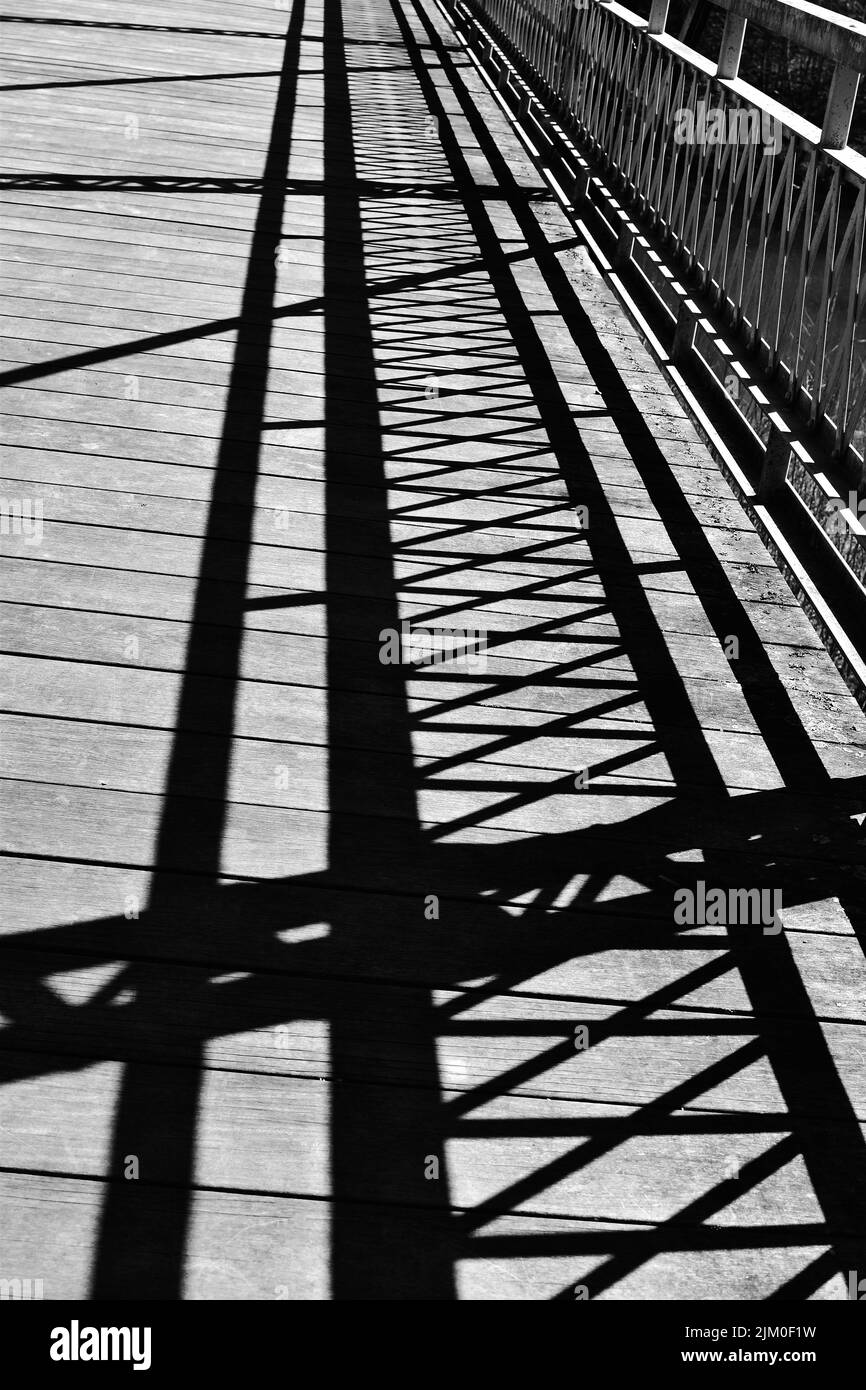 A vertical grayscale shot of the shadows of railings on a bridge Stock Photo