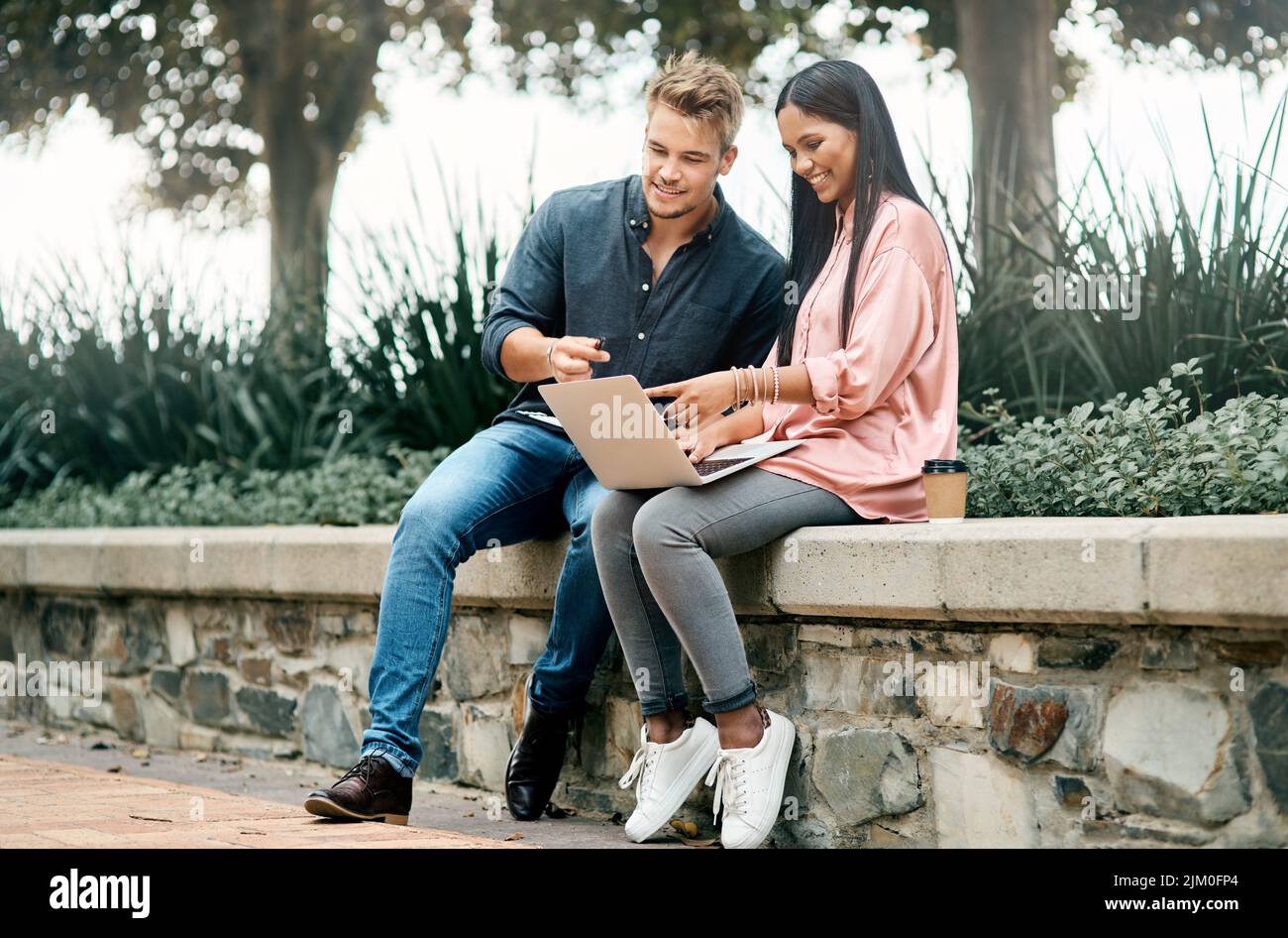 Forget the mistake, remember the lesson. two young students using a laptop while sitting outside on campus. Stock Photo
