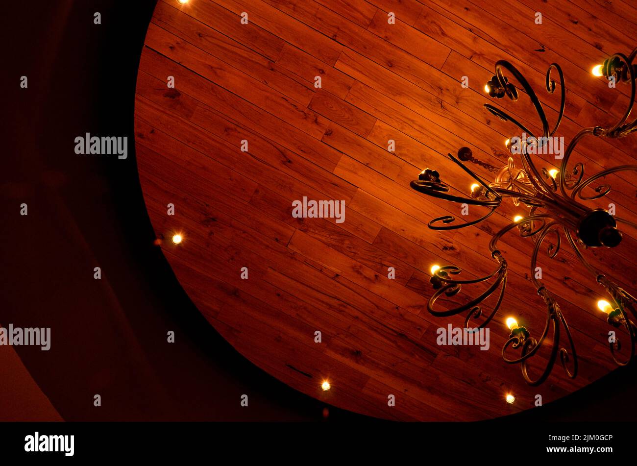 A low-angle shot of a lit chandelier hanging on a wooden ceiling Stock Photo