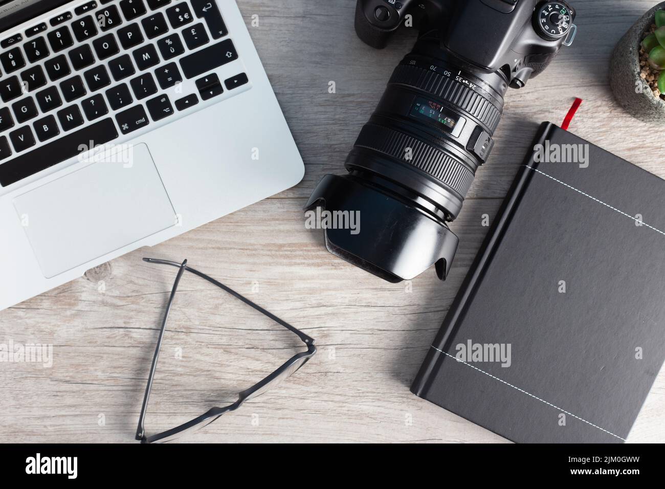 The photographer workstation with a camera, laptop, glasses on the wooden table Stock Photo