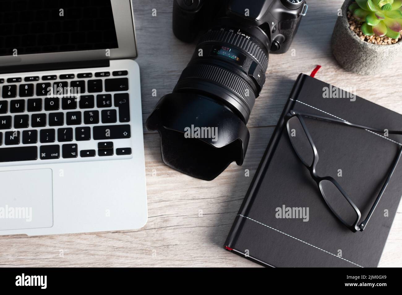 The photographer workstation with a camera, laptop, glasses on the wooden table Stock Photo