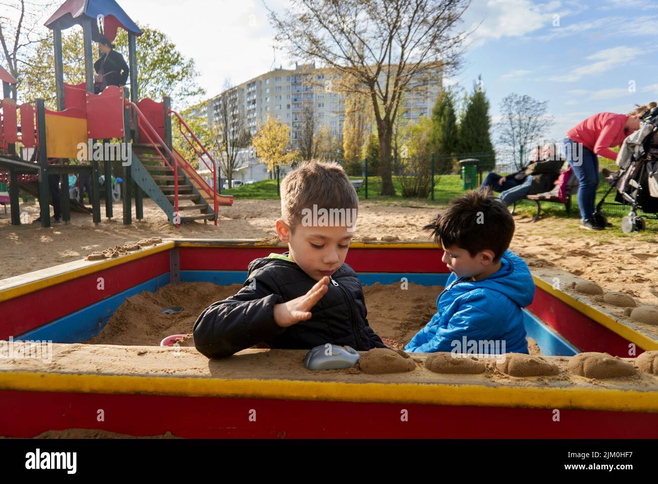 A view of two young boys playing with plastic toys in a sandpit at a playground Stock Photo