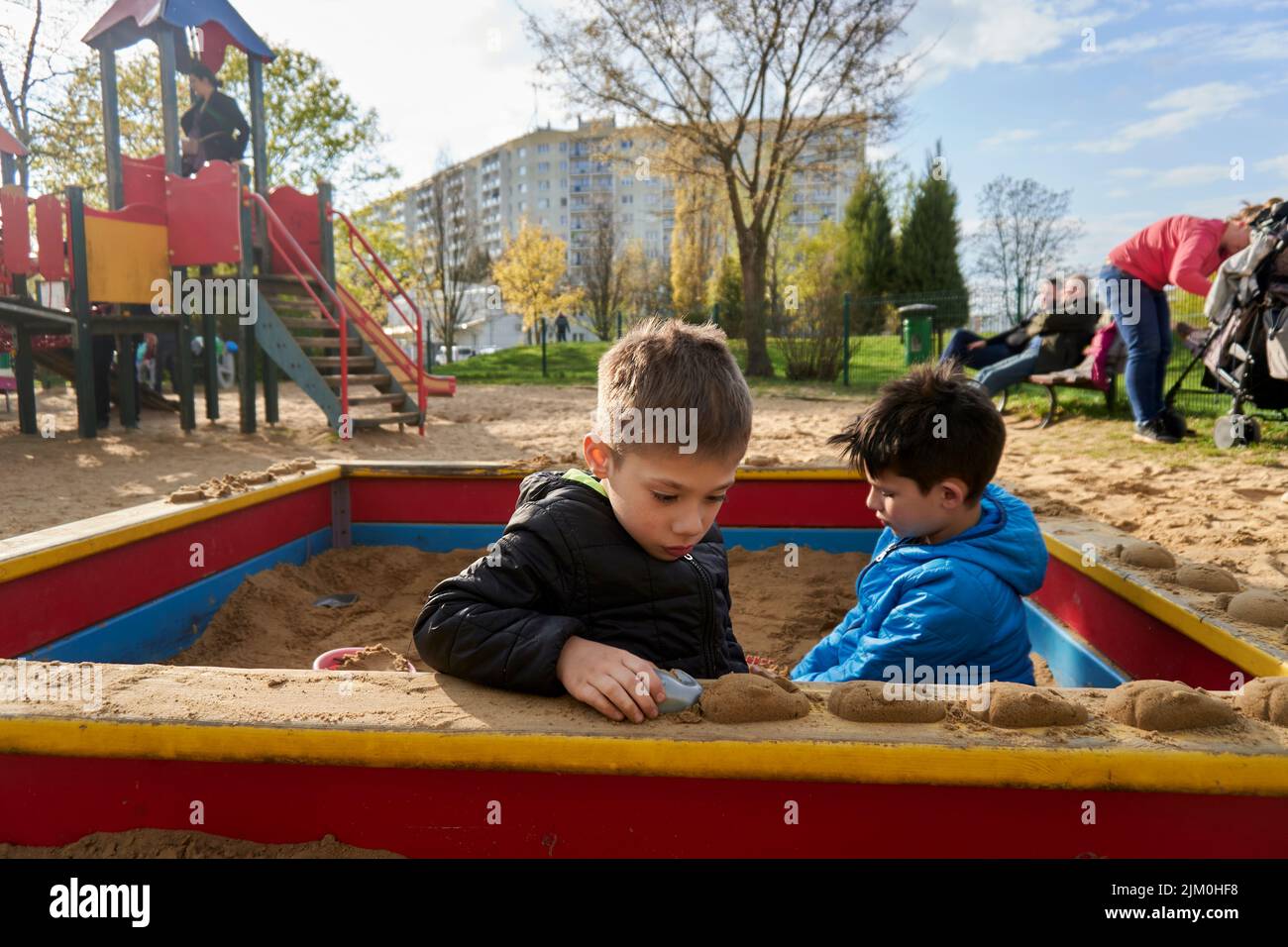 A selective of two young boys playing with plastic toys in a sandpit at a playground Stock Photo