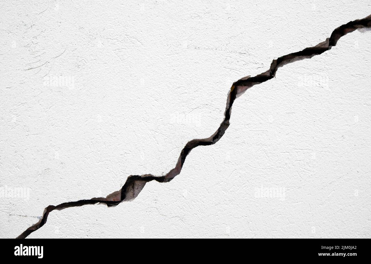 Long deep crack on the damaged wall as texture or background Stock Photo
