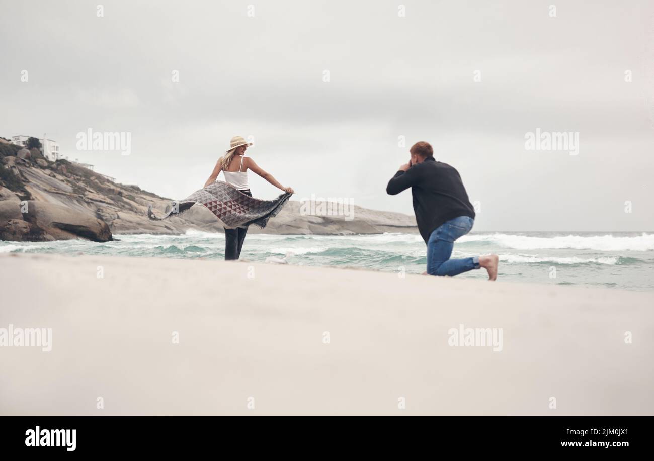 Pictures are better with a good view. a man taking pictures of his girlfriend while spending time at the beach. Stock Photo