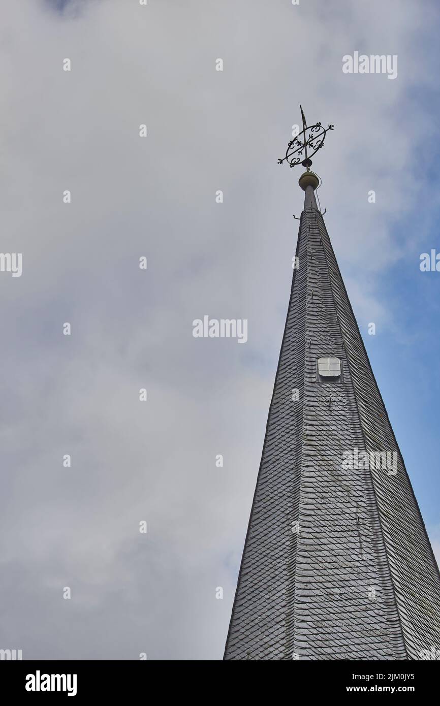 A vertical shot of The Roman Catholic parish church tower of the Holy Trinity in Monreal, Germany with a cloudy blue sky Stock Photo