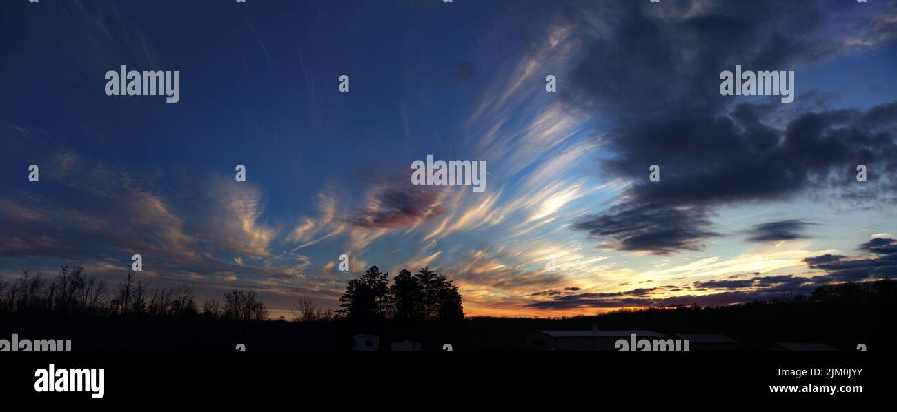A silhouette of trees under cloudy sky during sunset Stock Photo - Alamy