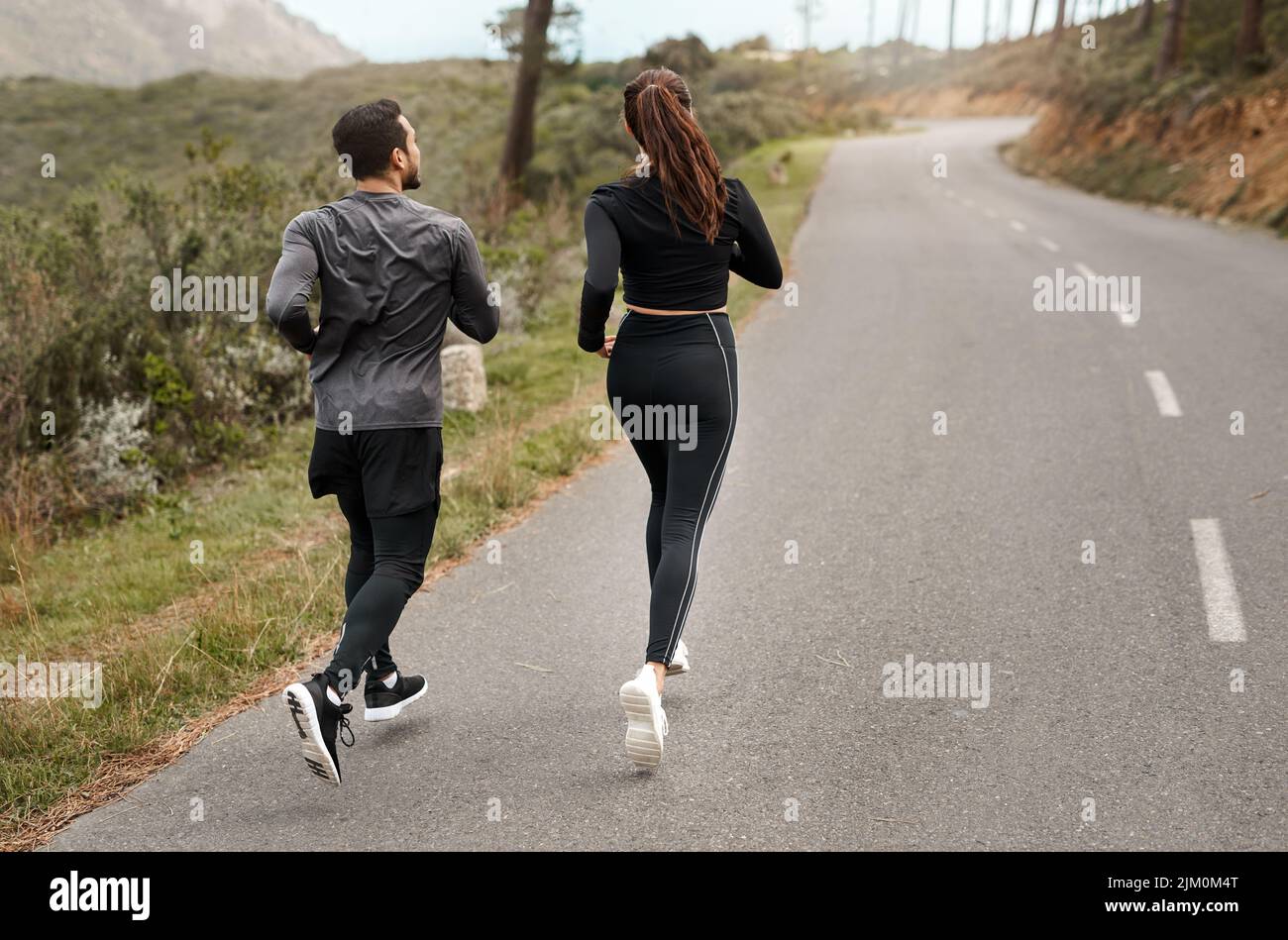 Final jog home. Full length shot of two unrecognizable athletes bonding together during a run outdoors. Stock Photo