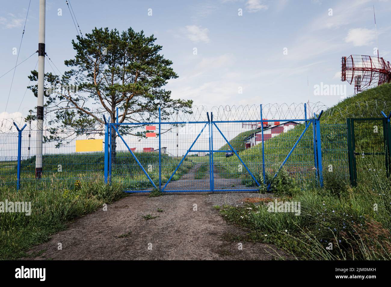 The restricted area is fenced with a metal fence, gates and barbed wire. Stock Photo