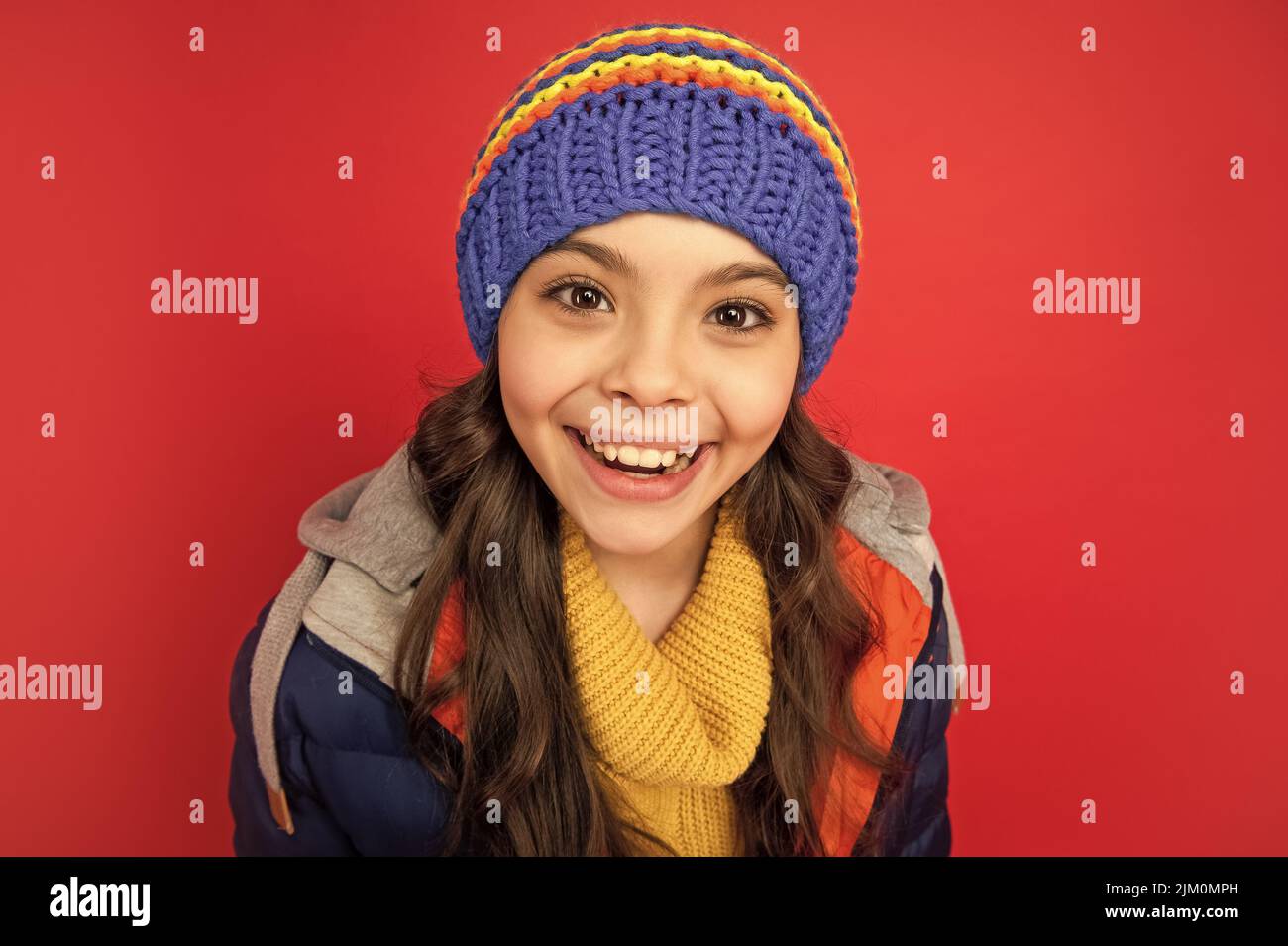 winter fashion. happy kid with curly hair in hat. female fashion model