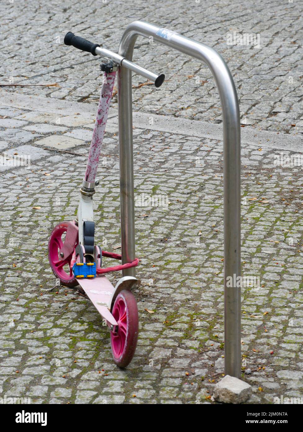 Metall stand with a pink Scooter on the pavement Stock Photo Alamy