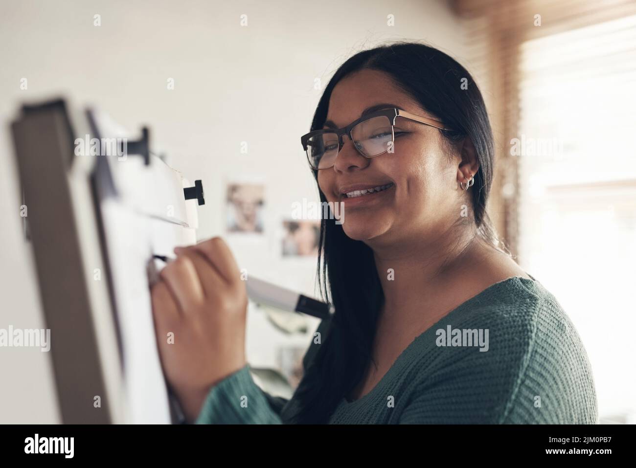 Where would we be without our teachers. a young woman using a whiteboard to teach a lesson from home. Stock Photo