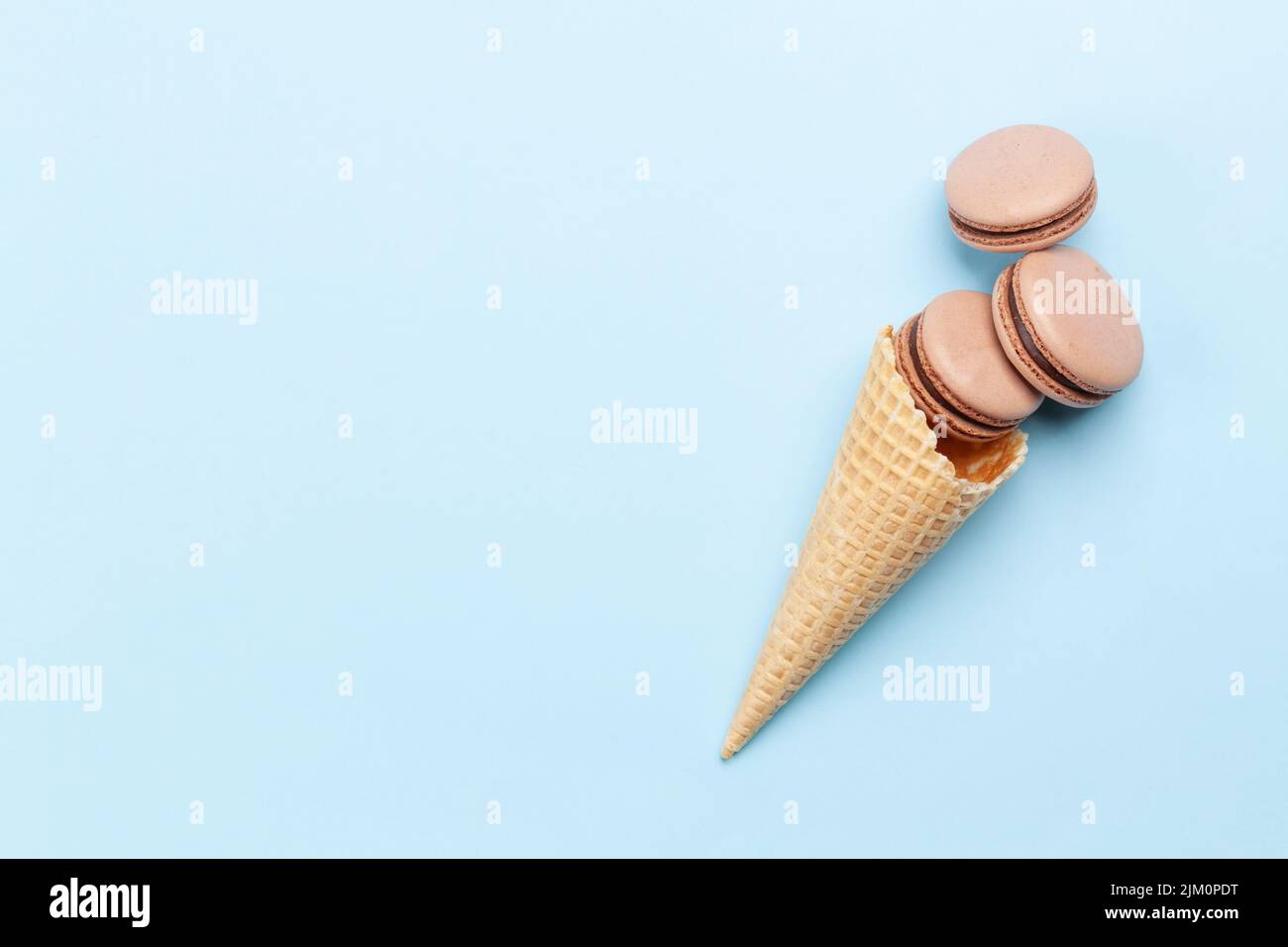 Various macaroon cookies in ice cream cones. Flat lay on blue ...