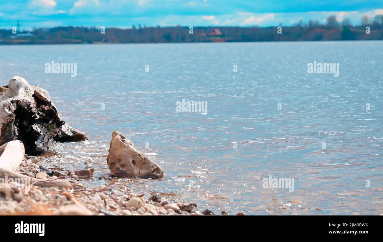 A bright summer day at the beach with small abstract-shaped rocks on the shore Stock Photo