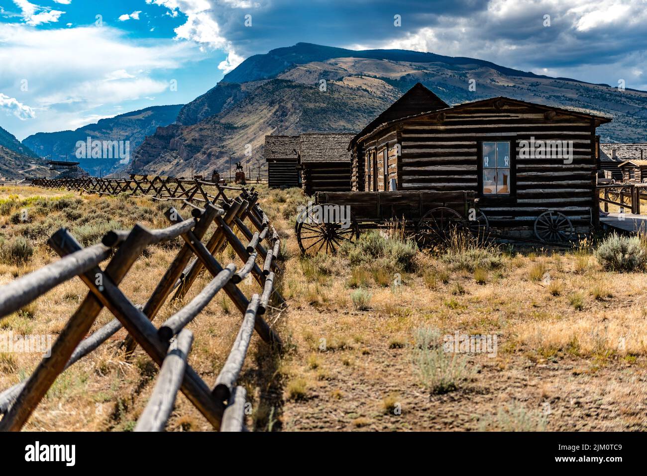 An old western house in a field with mountains in the background in