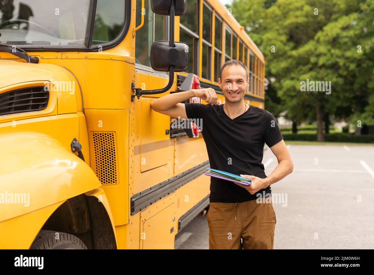 Portrait of teacher standing near the school bus Stock Photo - Alamy