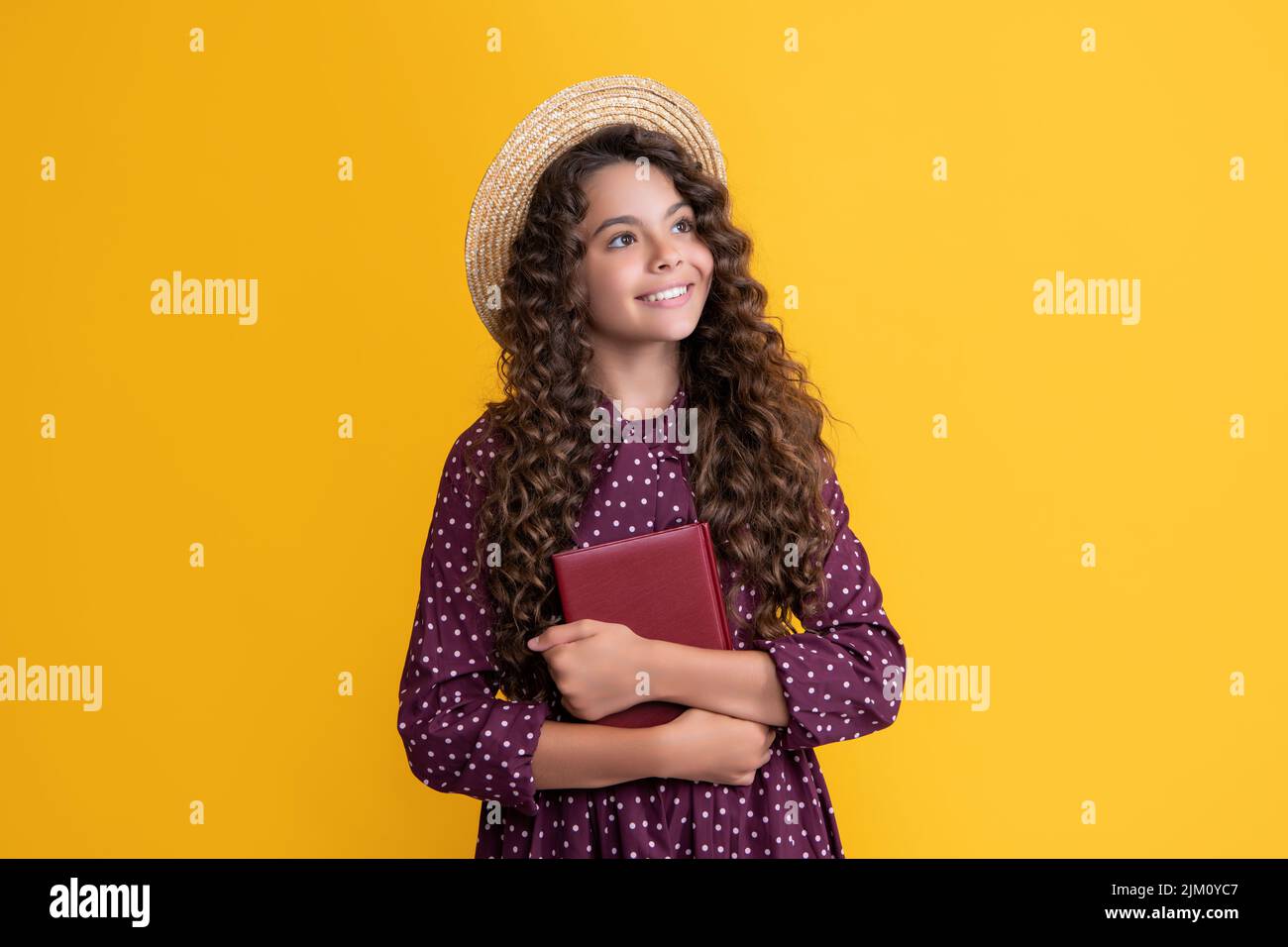 cheerful kid with frizz hair hold book on yellow background Stock Photo