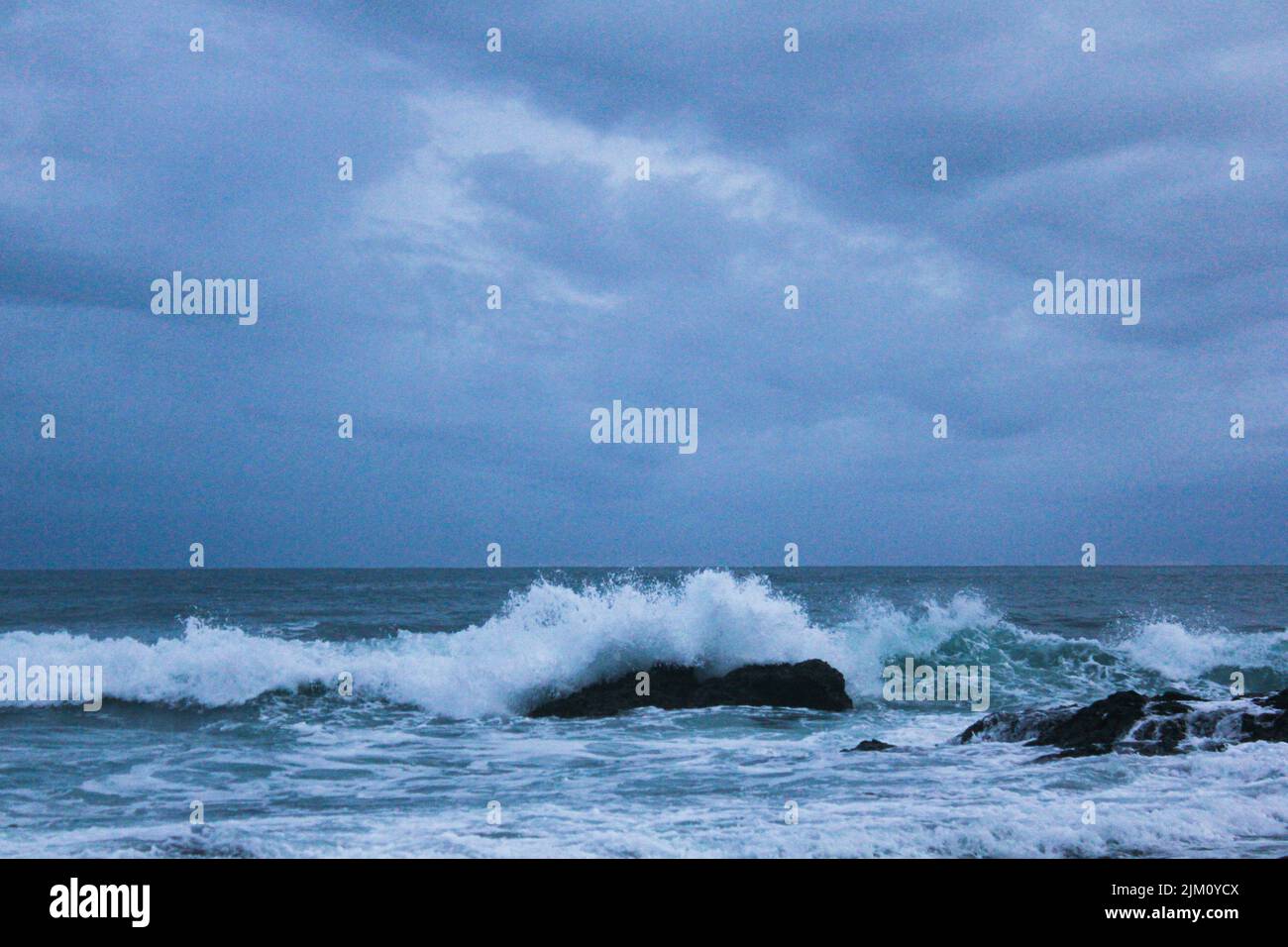 A beautiful landscape of crashing waves on a cloudy day Stock Photo