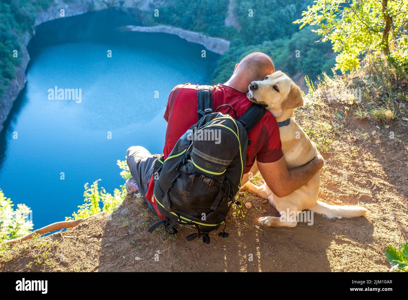 A man hugging his Labrador Retriever dog near a lake Stock Photo - Alamy