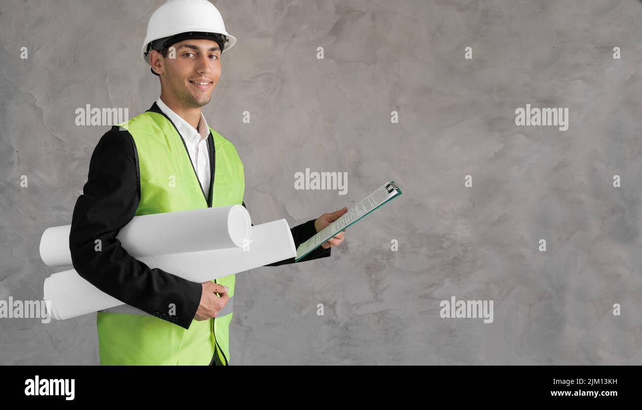 Young arabic civil engineer holding paperwork blueprint roll standing
